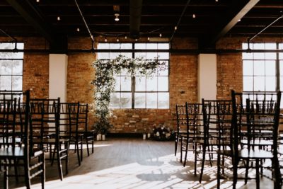Tenth Ward wedding ceremony image with floral altar arrangement and black chivari chairs